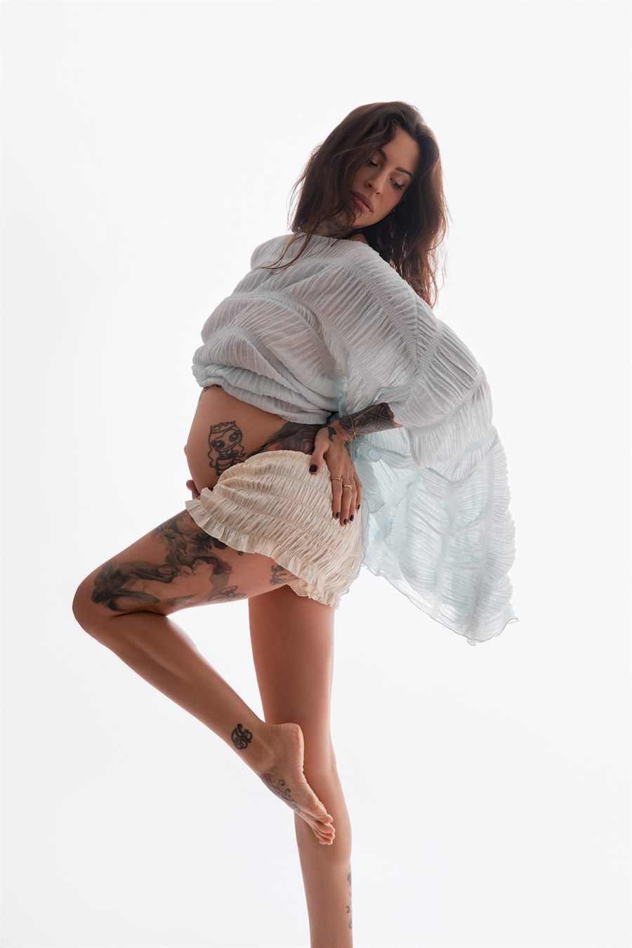 Future maman en tenue claire dans un studio lumineux