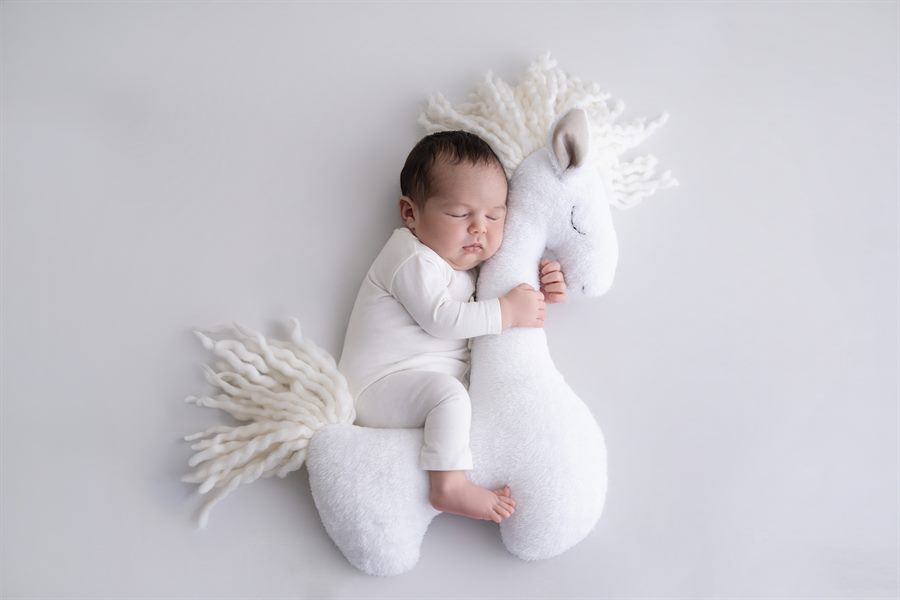 Bébé endormi contre une peluche blanche